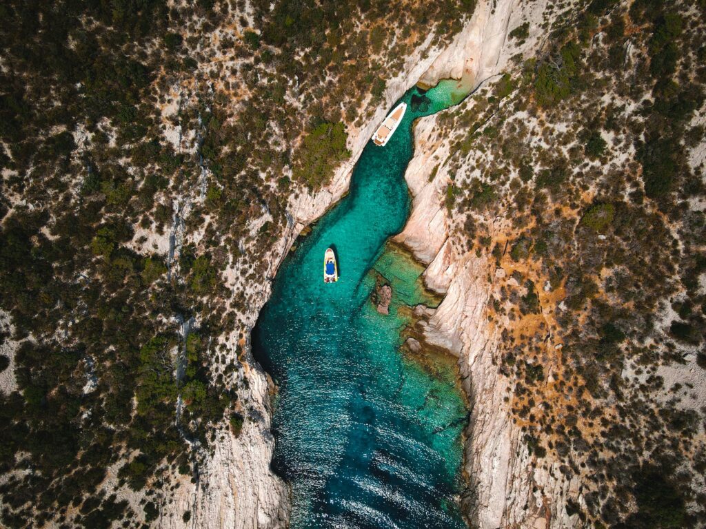 Stunning aerial view of boats in a turquoise coastal inlet surrounded by rugged cliffs.